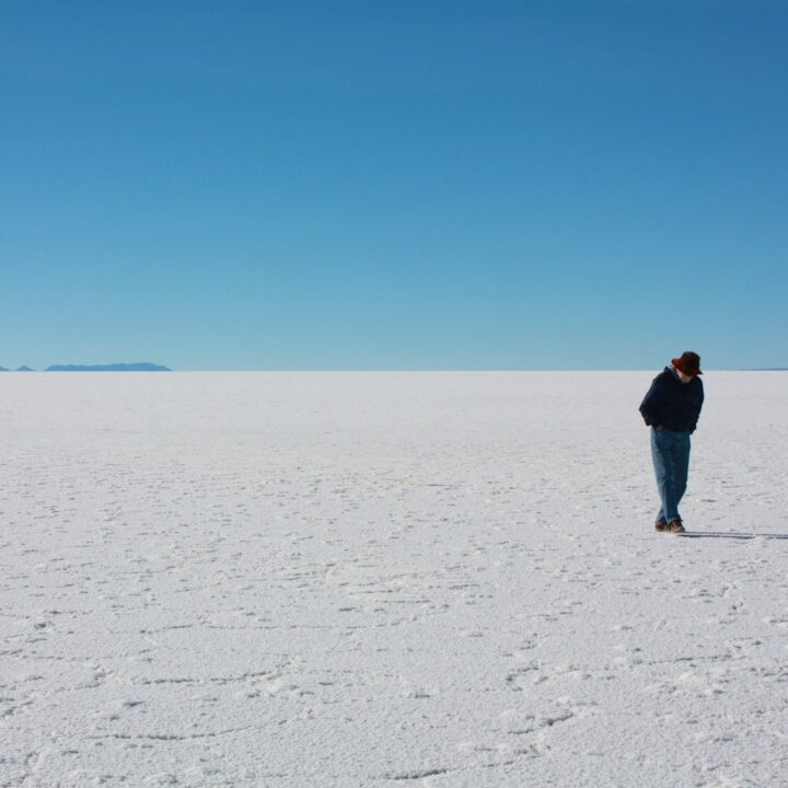 man in black jacket walking on white sand during daytime